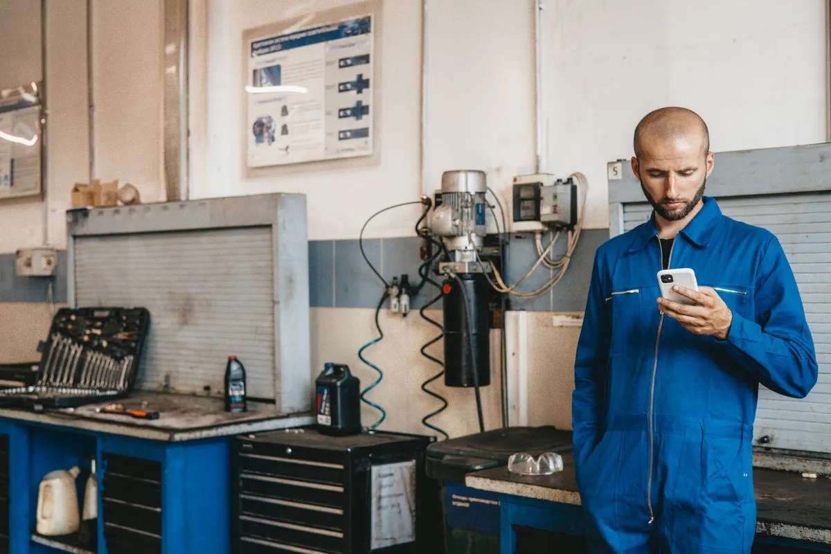 Technicien en combinaison utilisant un téléphone sur le terrain pour ouvrir l'ordre de travail