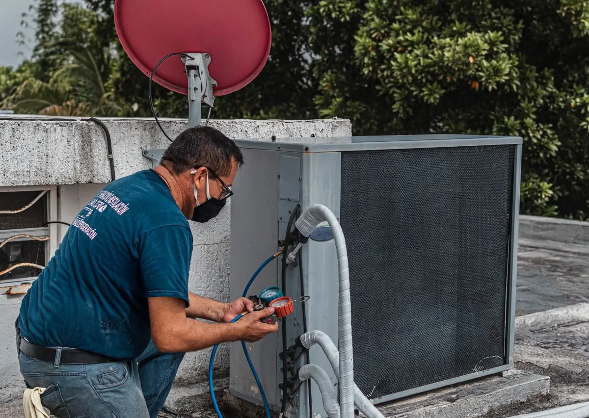 Technicien CVC utilisant un manomètre et des outils sur un climatiseur