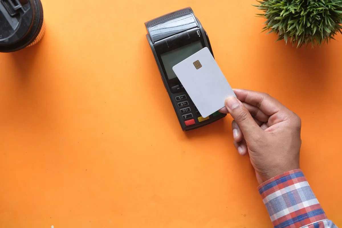 Person making a contactless payment with a credit card on a card reader