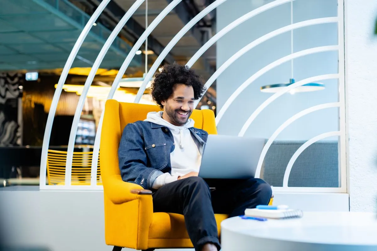 Man smiling while approving something on a laptop