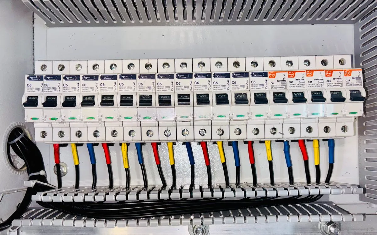 Tablero eléctrico de distribución organizado con disyuntores y cableado codificado por color