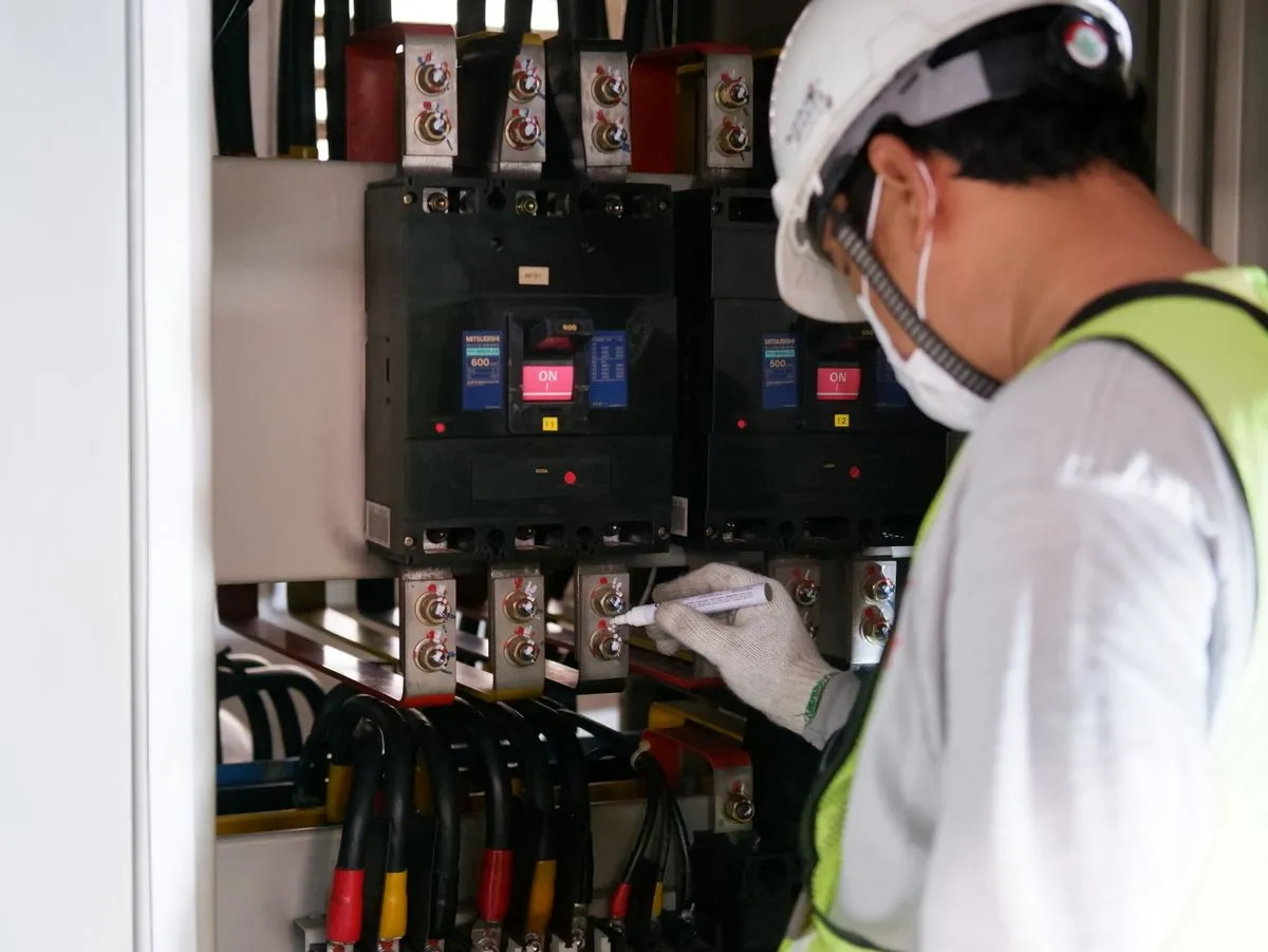 Técnico con EPP haciendo mantenimiento en tableros eléctricos en un entorno industrial